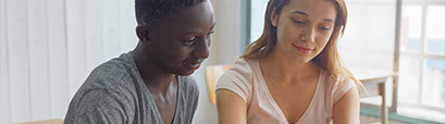 A woman speaking to a man at a help desk.